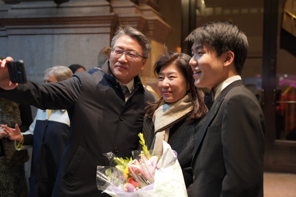 Ambassador Jongin Bae and and his wife, Junghee Lee take the opportunity for a 'selfie' with Sae Yoon Chon, outside the Weill Hall